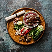 Ingredients for cooking Asian food with Tiger shrimps, udon noodles, mushrooms, greens, vegetables, spices on bamboo tray