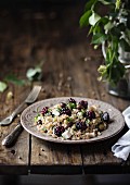 Cereal salad with spelt, olives, cheese, blackberries, basil on wooden table