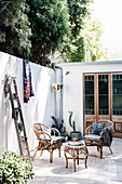 Wicker chairs and wooden ladder on the sunny courtyard terrace