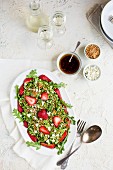 Strawberry Arugula Salad with Hibiscus Vinaigrette served with white wine on a white plaster background