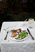 Roasted chicken legs served with millet and green peas
