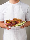 A man holding a plate of corned beef sandwiches