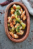 Chilli prawns with herbs in a rustic serving dish (top view)