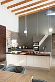 Elegante Einbauküche an grauer Wand und Kochinsel in hohem Raum