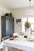 Table festively set in white in front of grey locker