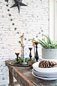 Candlesticks and wintry decorations on table in front of brick wall