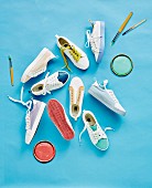 Various sneakers, paint lids and brushes on a blue background