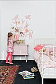 Mädchen am Nachttisch im rosafarbenen Kinderzimmer