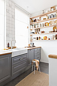 Kitchen accessories in shades of brown on wall-mounted shelves in kitchen with grey cabinets
