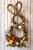 Bunny-shaped Easter wreath decorated with flowers on wall