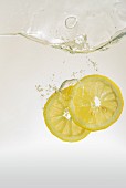 Zitronenscheiben fallen ins Wasser