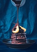 Chocolate sauce drizzling over chocolate pancakes with poached pears