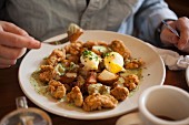 Poached eggs over roasted home fries with creamed spinach and crispy fried oysters