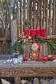 Advent arrangement of four lit red candles in basket