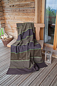 Brown blanket made from strips of various fabrics with decorative green seams