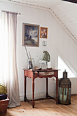 Large lantern on floor next to small red table with vintage accessories