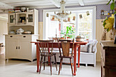 Roter Tisch mit Stühlen und Bank in skandinavischer Landhausküche