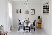 Black and grey spoke-back chairs around table in white dining room
