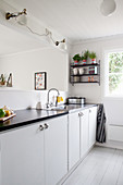 Simple white kitchen with black worksurface and serving hatch