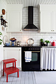 Red stool in Scandinavian country-house kitchen with classic cooker