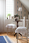 Two white chairs with ruffled seat cushions at antique side table