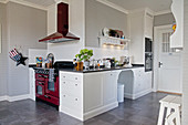 White panelled cabinets and red cooker in large country-house kitchen