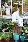 Potted plant, planters and small, white ornamental house outside greenhouse