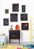 Children's drawings on blackboards with colourful frames on white wall