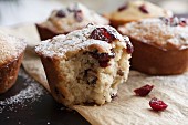 Freshly baked cranberry muffins on parchment paper with sugar icing