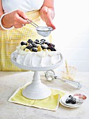 Simple Pavlova with bananas and blackberries is covered with sugar