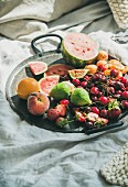Tray full of fresh seasonal fruit over light blanket background