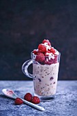 Overnight oats in almond milk topped with fresh raspberries and coconut flakes