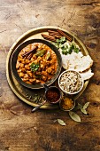 Chicken tikka masala spicy curry meat food in copper pan with rice and naan bread on wooden background