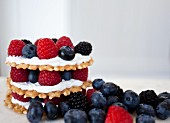 Stacks of wafer cookies, icing and mixed berries with a white background