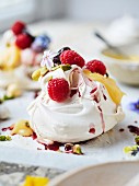 Lemon, raspberry, pistachio meringue with lemon curd, poached raspberries, and vanilla cream, edible flowers