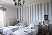 Twin beds in blue and white bedroom with striped accent wall