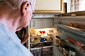 Elderly man looking in a fridge