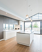 Offene Küche mit Kochinsel unter dem Dach mit verglaster Giebelwand