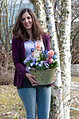 Frau bringt Topf mit Hyacinthus ( Hyazinthen ), Viola cornuta 'Lavender Blush'