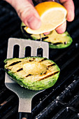 Grilled avocado being drizzled with lemon juice