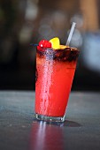Roter Cocktail mit Cocktailspiesschen auf Bartheke