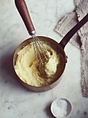 Mashed potatoes with a whisk in a saucepan
