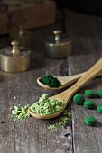 Spirulina tablets and spirulina powder on wooden spoons