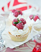 Cupcakes decorated with whipped cream, meringue pieces and raspberries