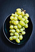 Green grapes in a bowl on a dark background