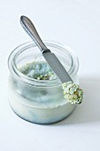 Homemade herb ointment in a jar and on the tip of a knife