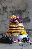 Gestapelte Pancakes mit frischen Beeren und Blumen
