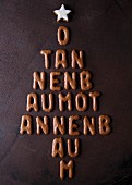 Letter-shaped biscuits arranged in the shape of a Christmas tree, reading 'O Tannenbaum' and topped with a star