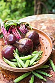 Beetroot and peas in a clay dish on a rusty table outdoors