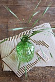 Gräser in einer grünen Vase auf abgerissenem Pappkarton